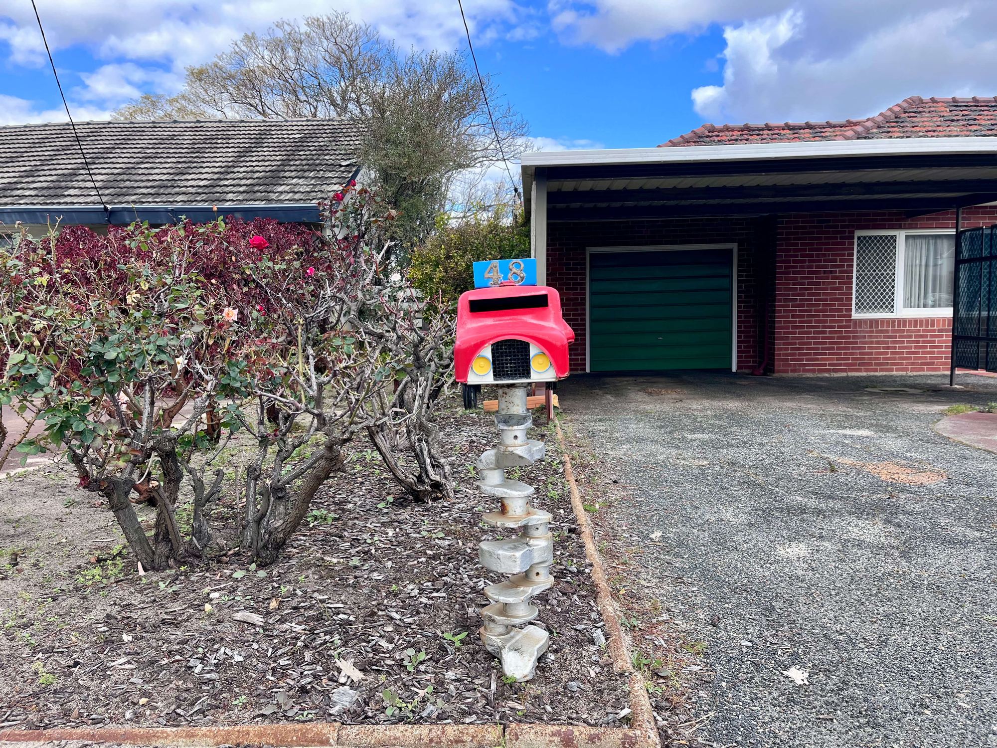 A red toy-truck letterbox numbered 48, mounted on a post made of stacked engine parts
